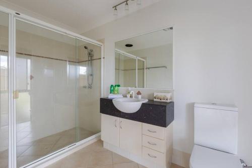 a white bathroom with a sink and a shower at Gold Coast Theme Parks With a Pool in Gold Coast