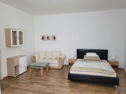 a bedroom with a bed and a couch and a table at Das Nest Boardinghouse Hamburg Niendorf in Hamburg