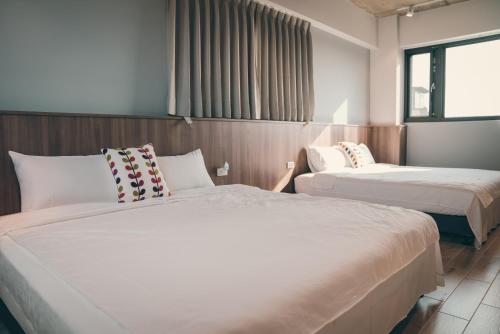 a hotel room with two beds and a window at Flower Garden B&B in Hengchun
