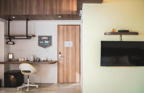 a room with a door and a chair and a television at Flower Garden B&B in Hengchun