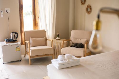 a bedroom with two chairs and a cat sleeping on a bed at Indie Beach Bungalows in Ko Chang