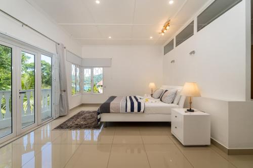a white bedroom with a bed and a window at Villa Jasmin in Bel Ombre