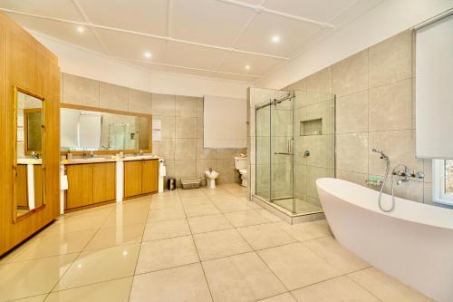 y baño con bañera, ducha y lavamanos. en Villa Jasmin, en Bel Ombre
