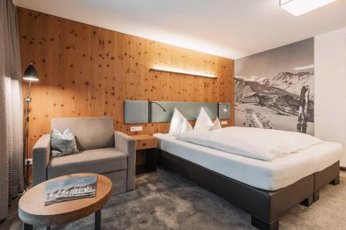 a bedroom with a bed and a chair and a table at Hotel Piz Buin in Ischgl