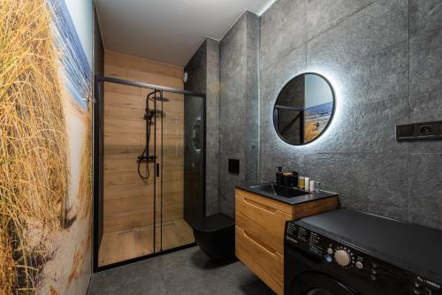 Un baño con ducha, lavabo y espejo. en Horyzont Apartamenty -Bałtycka2 - SAUNA & FITNESS - ŚNIADANIA, en Kołobrzeg