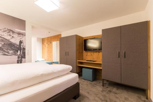 a bedroom with a bed and a flat screen tv at Hotel Piz Buin in Ischgl