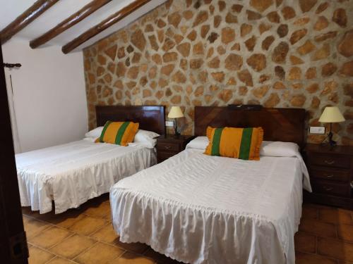 a bedroom with two beds and a stone wall at Casa Rural Cortijo la Jimena in Caravaca de la Cruz