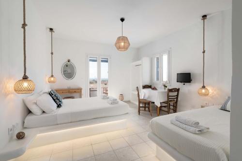 a white bedroom with two beds and a dining room at Manolis Studios in Kastraki Naxou