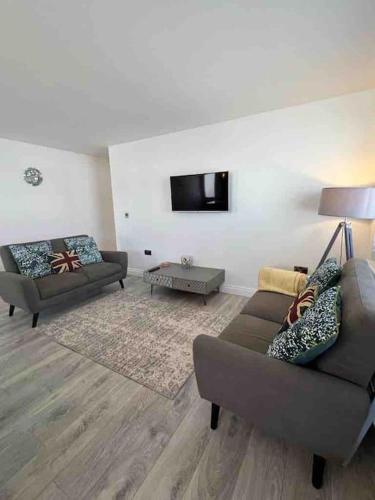 a living room with two couches and a flat screen tv at The Emslie Road Beach Flat in Falmouth