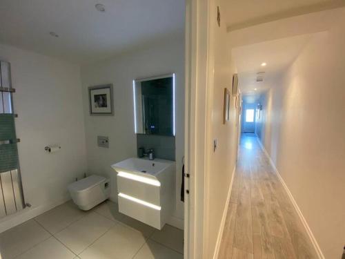 a white bathroom with a sink and a toilet at The Emslie Road Beach Flat in Falmouth