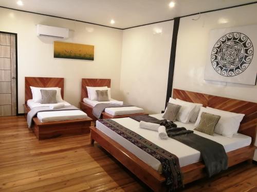 three beds in a room with wooden floors at Keira Backpackers in El Nido