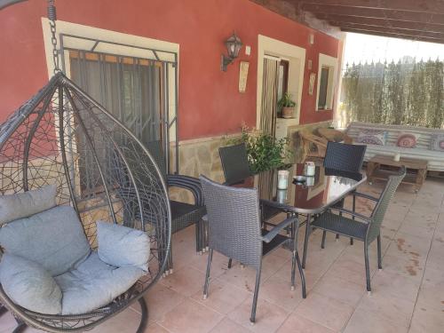 porche con mesa, sillas y columpio en Casa Rural Cortijo la Jimena, en Prados