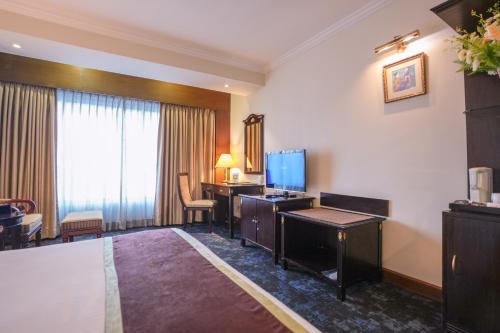 a hotel room with a bed and a desk and a television at Hotel Sarina in Dhaka