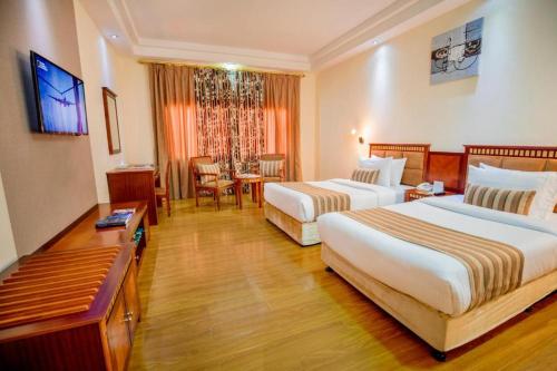 Großes Hotelzimmer mit 2 Betten und einem Tisch in der Unterkunft Hamdan Plaza Hotel Salalah, an HTG Hotel in Salalah