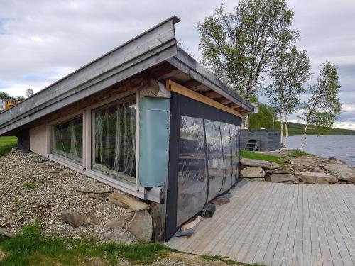 eine kleine Hütte mit einem Fenster und einer Katze, die draußen sitzt in der Unterkunft Røros Arctic Dome in Glåmos