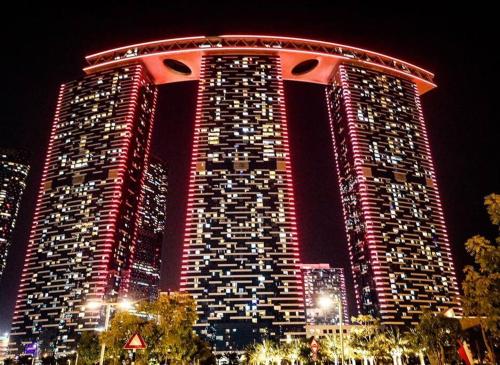 a large building with red lights on it at night at Cozy 1BR in Gate Tower in Abu Dhabi