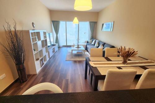 a living room with a couch and a table and chairs at Cozy 1BR in Gate Tower in Abu Dhabi