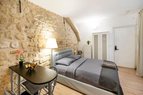 - une chambre avec un lit, une table et un mur en pierre dans l'établissement Paris entre Opéra et Montmartre, à Paris