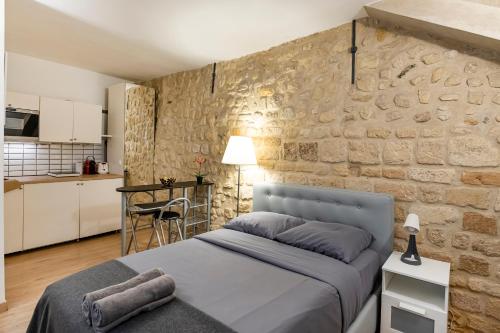 une chambre avec un lit et un mur en pierre dans l'établissement Paris entre Opéra et Montmartre, à Paris
