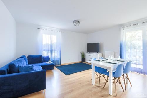 a living room with a blue couch and a table at Horyzont Apartamenty - Osiedle Bursztynowe- Śniadania!!! in Kołobrzeg