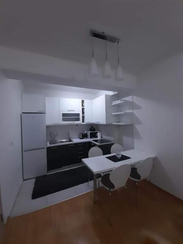 a kitchen with white cabinets and a table and chairs at Astrid Apartment in Skopje