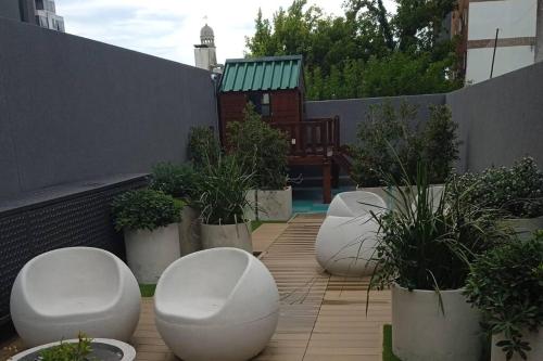 a row of white chairs and potted plants on a patio at A estrenar en Punta Carretas in Montevideo