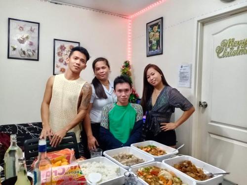 a group of people standing around a table with food at Two-Bedroom at San Remo Oasis in Cebu City