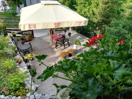 a patio with an umbrella and chairs and flowers at Vila Zorka in Nova Varoš