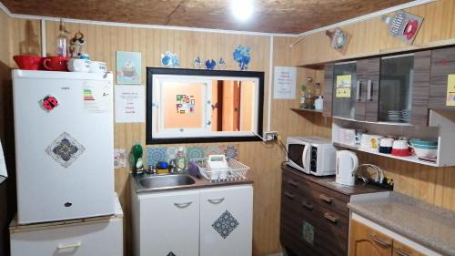 a kitchen with a white refrigerator and a sink at "Mi Hostal Tu Casa" Hostal Familiar SOLO EMPRESAS, TURISTAS y VIAJEROS in Puerto Montt