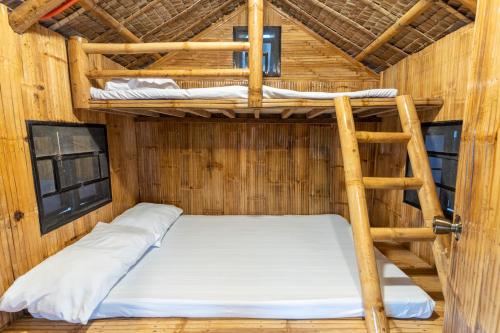 two bunk beds in a wooden room with a ladder at Bamboo Paraiso Resort at Bolo Beach in Alaminos