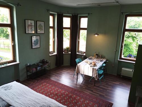 a room with a table and a bed and windows at zur Friedrichsruh in Oelsnitz