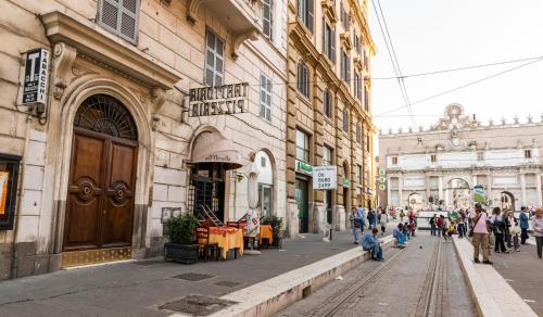 un grupo de personas caminando por una calle al lado de un edificio en Martina a Piazza del Popolo, en Roma