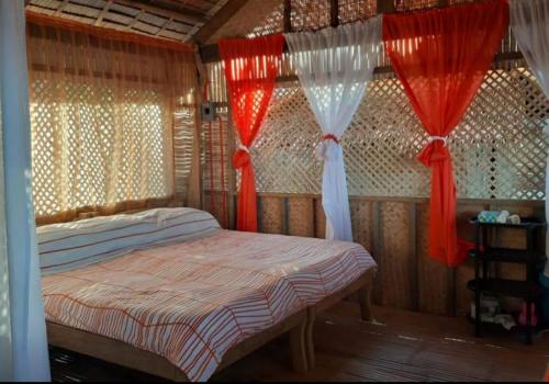 Schlafzimmer mit einem Bett mit roten und weißen Vorhängen in der Unterkunft Beachaus Resort 