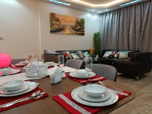 a dining room table with plates and glasses on it at Luxury two bedroom شقة فخمة وكبيرة غرفتين in Ajman