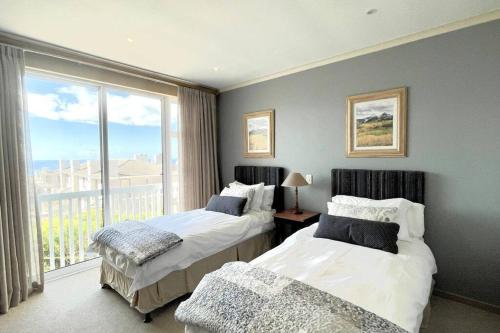 a bedroom with two beds and a large window at Luxury at Pinnacle Point - 3 Bedroom Villa in DʼAlmeida