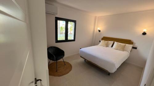 a bedroom with a bed and a window and a chair at Casa Goldberg in Paguera