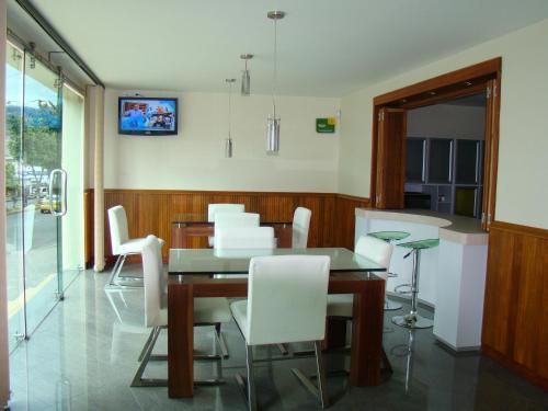 une salle à manger avec une table et des chaises blanches dans l'établissement Apartahotel Vincent Suites, à Pasto