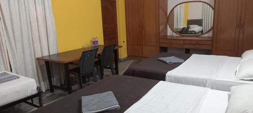 Habitación de hotel con 2 camas, mesa y espejo en Shalom Guest House, en Panaji