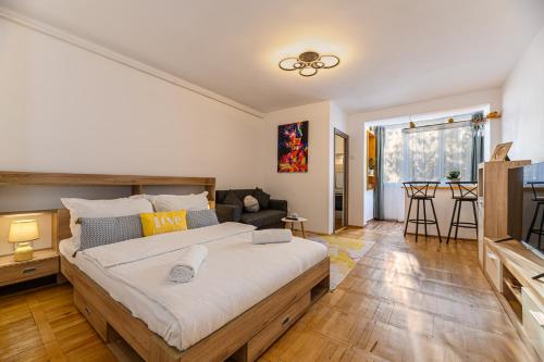 a bedroom with a large bed and a living room at JAD Family Apartments & Studios Calea Bucuresti in Braşov