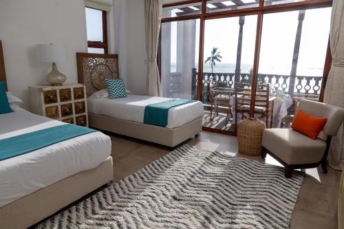 a bedroom with two beds and a living room with a balcony at Sultan Palace Beach Retreat Mombasa in Mombasa
