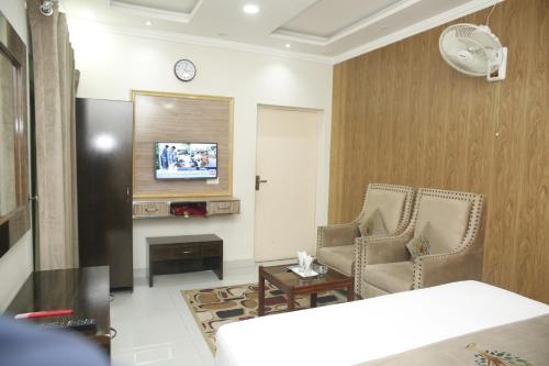 a living room with two chairs and a tv at Park View Hotel Gulberg in Lahore