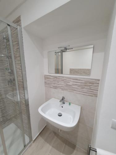 een witte badkamer met een wastafel en een douche bij Appartamento Il Castello in Casale Monferrato
