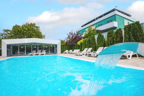 a swimming pool with a water fountain in front of a building at Ośrodek Sea Star Premium in Sarbinowo