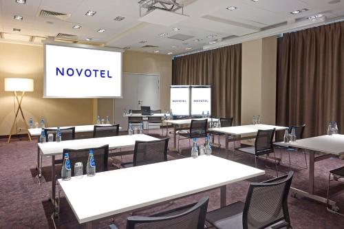 a conference room with white tables and chairs and a screen at Novotel Warszawa Centrum in Warsaw