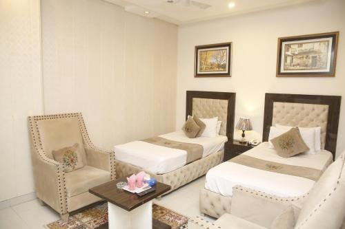 a hotel room with two beds and a table and chairs at Park View Hotel Gulberg in Lahore