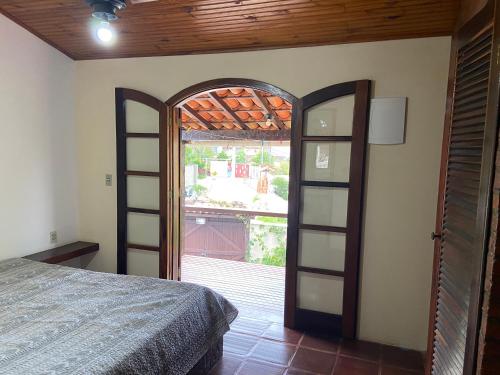 a bedroom with a bed and an open door at Casa de 5 suítes e piscina em Geribá in Búzios