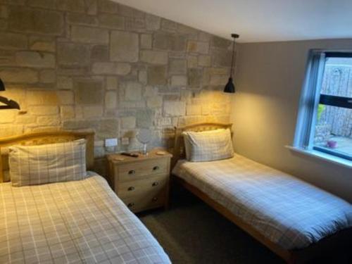a bedroom with two beds and a stone wall at Mason's Arms in Norham