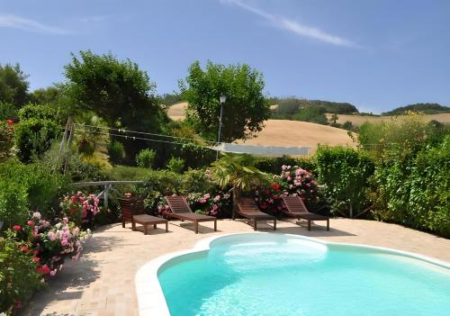 a swimming pool in a garden with chairs and flowers at Agriturismo La Valle Dimenticata in Urbania