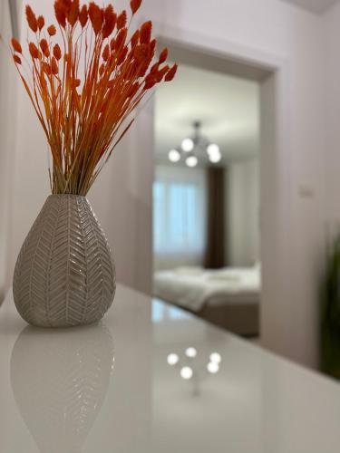 a white vase with red flowers sitting on a table at ESI Apartments #Central with Garage in Timişoara