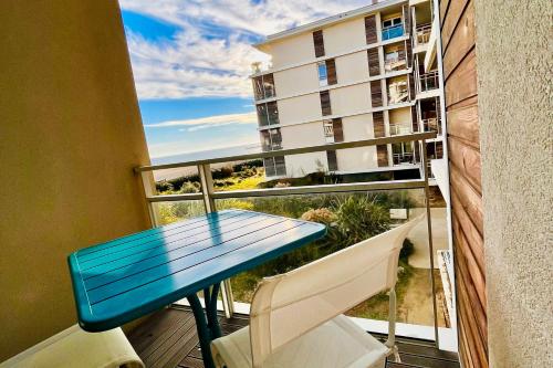 une table bleue et des chaises sur un balcon avec un bâtiment dans l'établissement Le Sunlight - T2 bord de mer, Parking, à Palavas-les-Flots